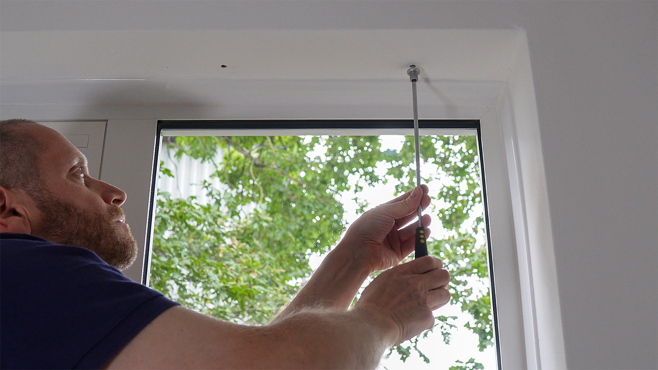 Attaching the cable kit's top inner fixing to the ceiling.