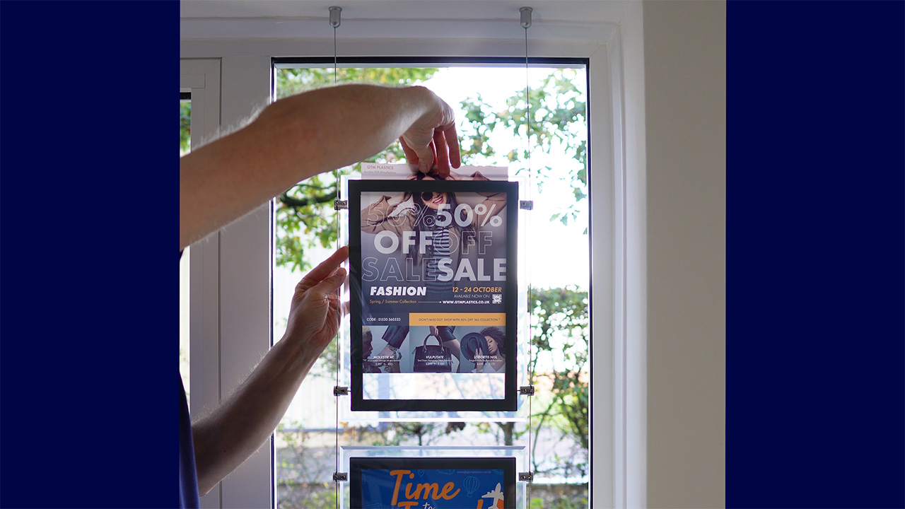 Inserting backlit film into one of the light pockets by flexing away the acrylic face panel.