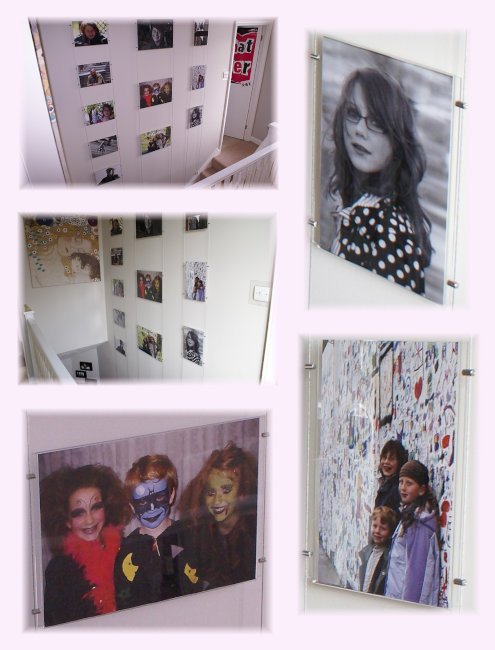 Cable-suspended poster holder displays mounted inside someone’s house, up against the wall in the stairway, showing of their family photos.