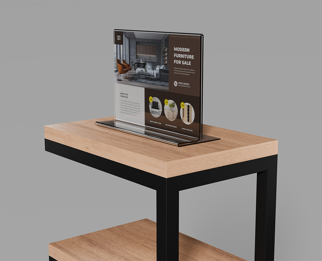 A free-standing upright acrylic poster holder placed on a wood and metal rectangular table. The poster is advertising modern furniture for sale.