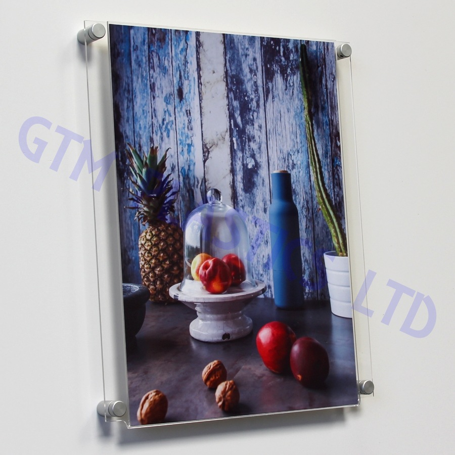 An acrylic easy access poster pocket/sleeve displaying a poster. Wall mounted stand-off clamps pass through the side-flanges to attach the pocket to the wall.